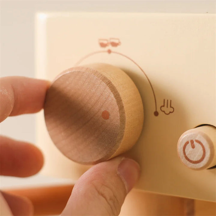Hand turning the large wooden dial on the toy coffee machine.