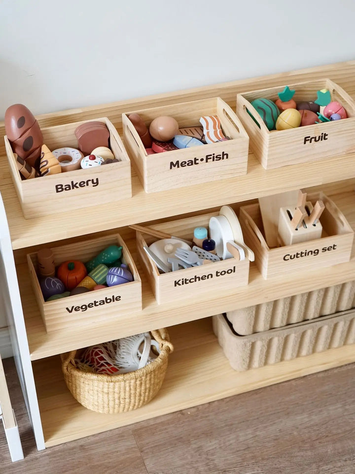 Wooden play food and kitchen-tool crates arranged on a shelf