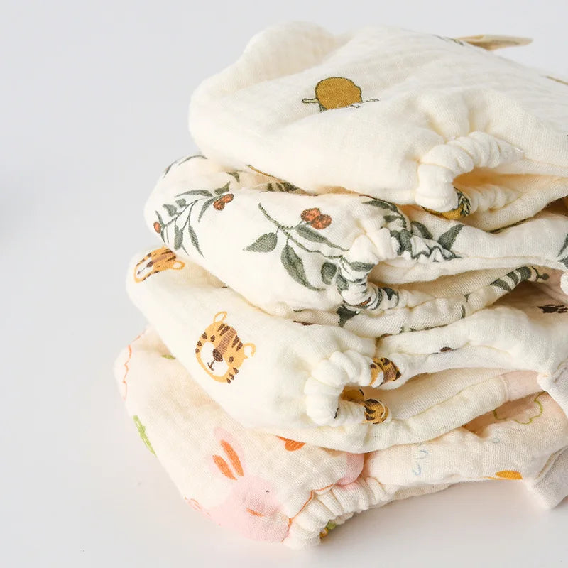 Stack of folded cotton cloth diapers in assorted fruit, leaf, and animal prints
