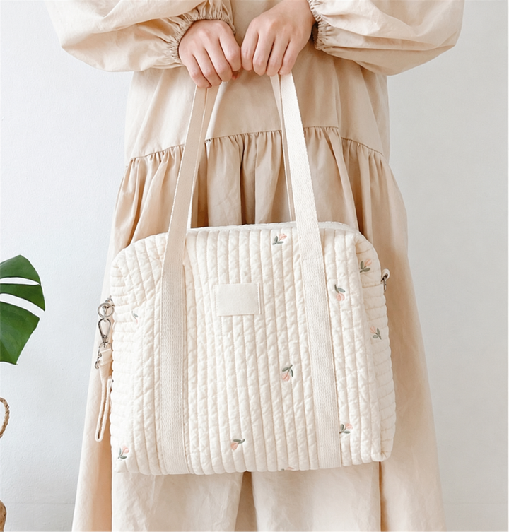 Printed quilted diaper bag held by its long fabric handles