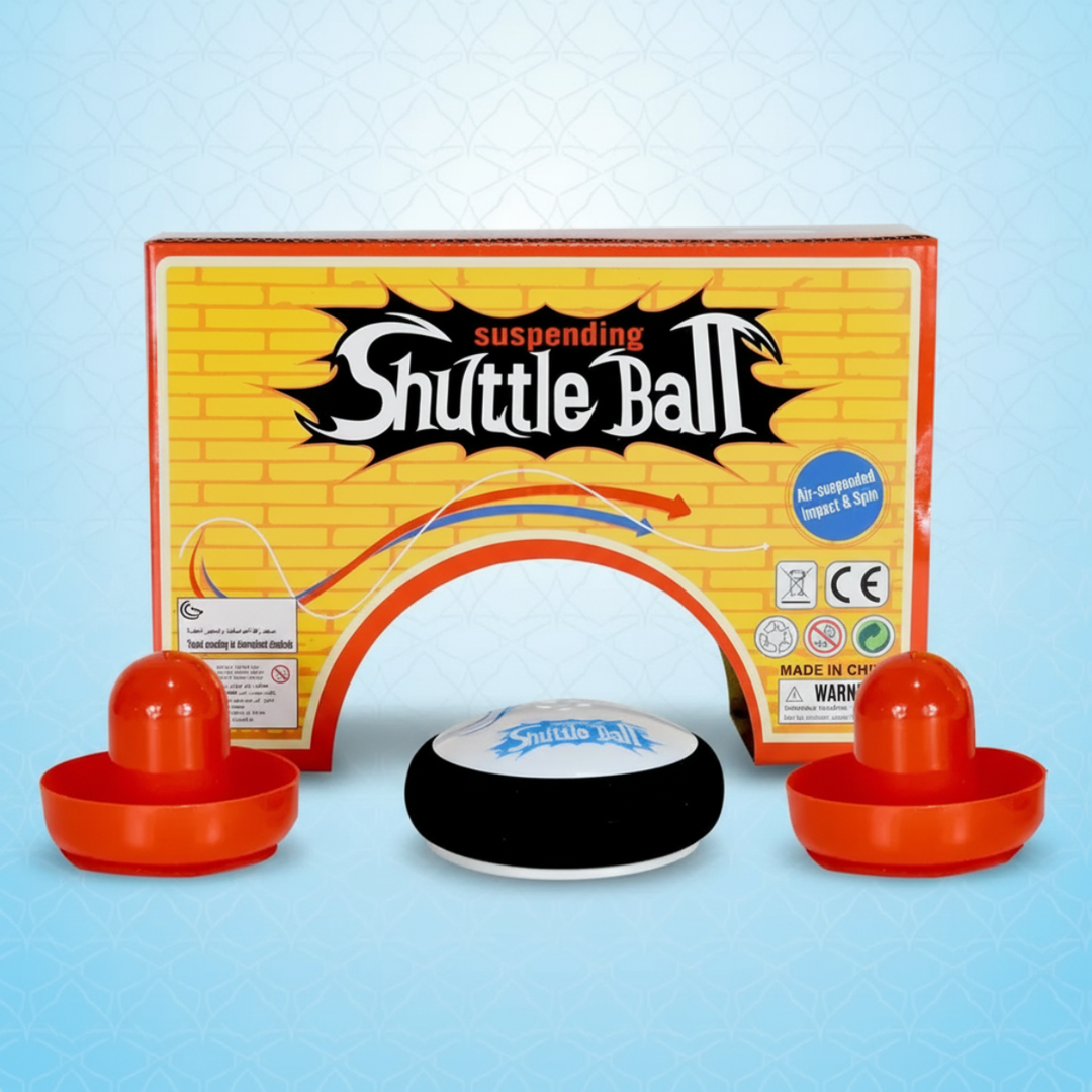 Two orange paddles and a black-and-white air hockey puck in front of the game box