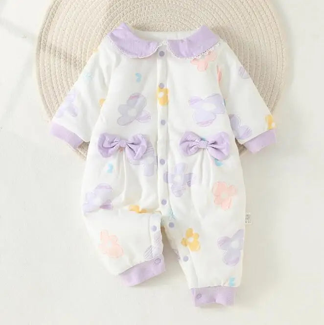 Baby pajamas with purple trim, a rounded collar, and two decorative bows