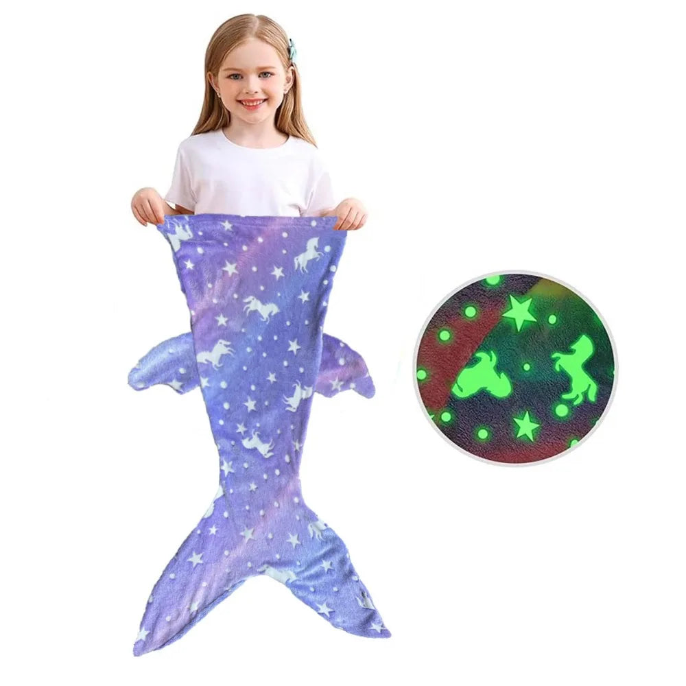 Child holding a purple mermaid sleeping bag with side fins and an inset of the glow-in-the-dark print.