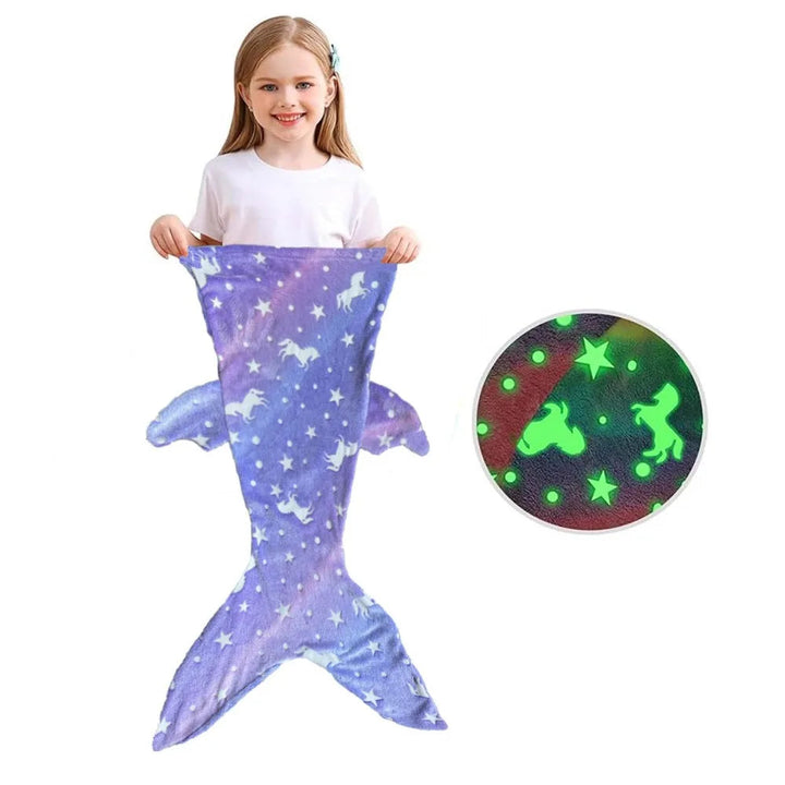 Child holding a purple mermaid sleeping bag with side fins and an inset of the glow-in-the-dark print.