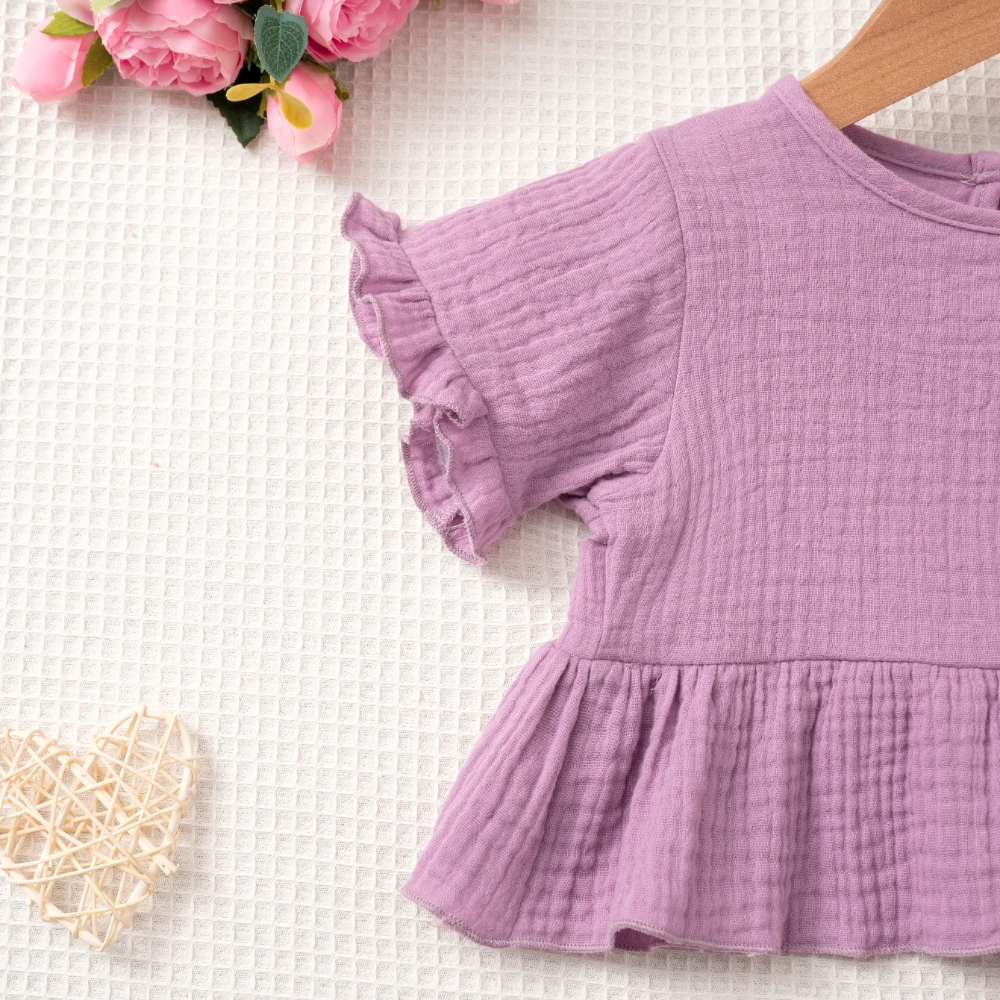 Purple top showing its ruffled butterfly sleeve and gathered hem