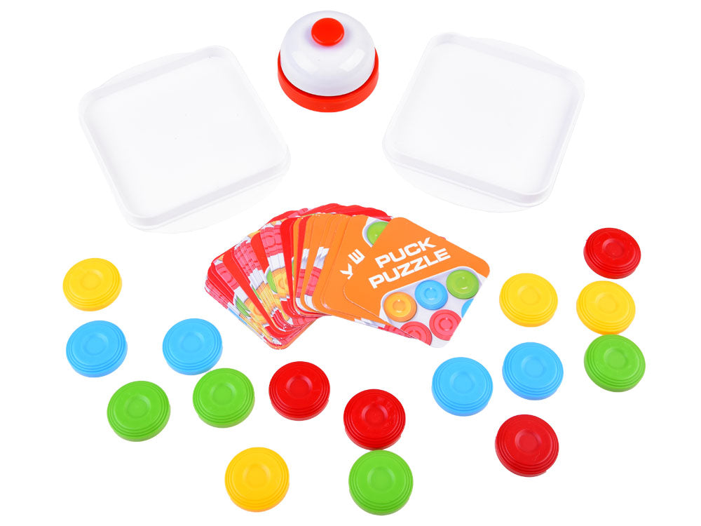 Two empty puzzle boards with loose colored disks, challenge cards, and a bell