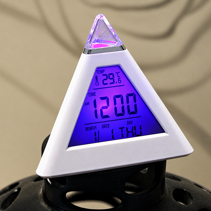 White pyramid alarm clock with a purple-lit digital display and pointed top.