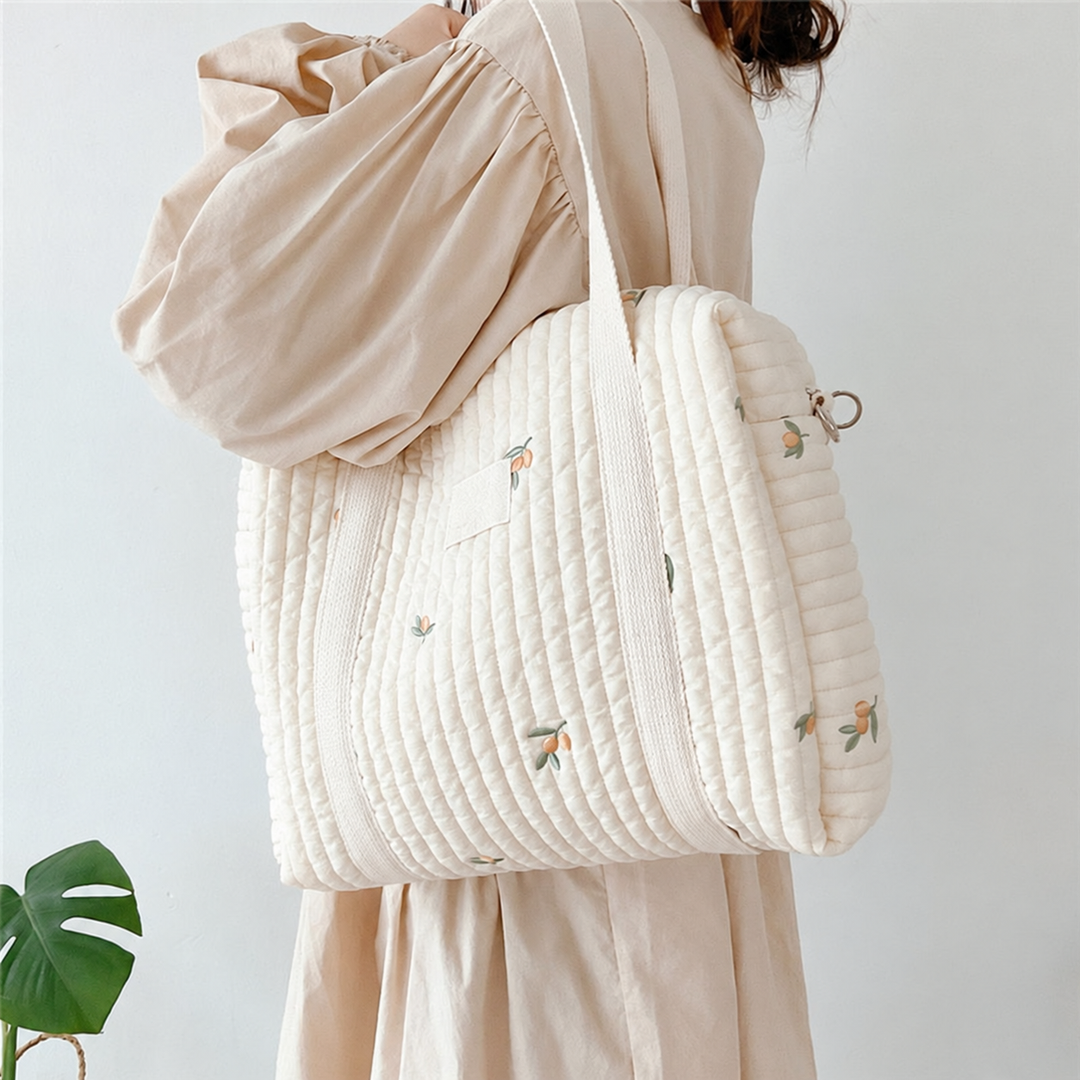 Side view of a cream printed diaper bag worn over the shoulder