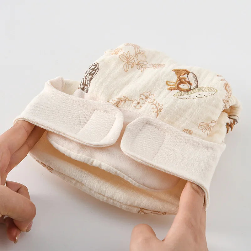 Hands stretch the waistband of a rabbit-print cloth diaper with hook-and-loop tabs