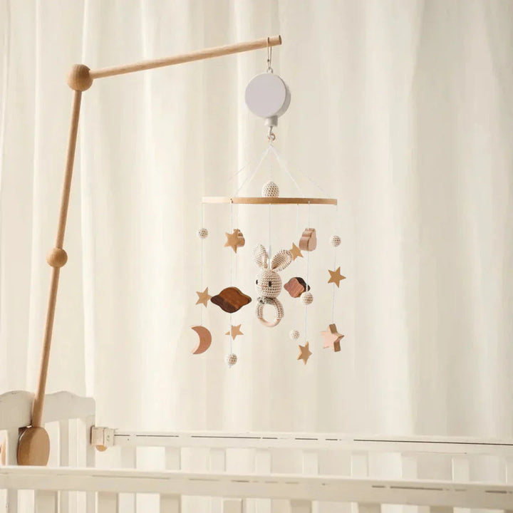 Rabbit baby mobile with moon and star shapes displayed on a wooden arm in a nursery