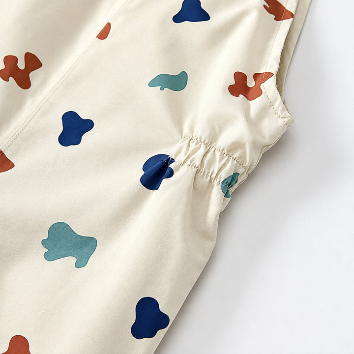 Gathered elastic at the side waist of the cream printed rain pants.