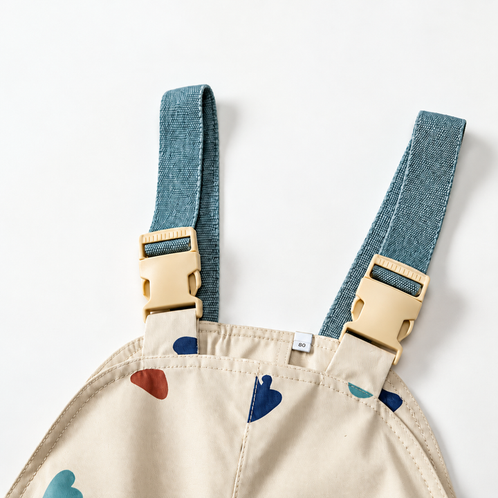 Teal shoulder straps and cream buckles at the top of the printed rain bib pants.