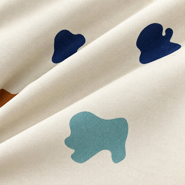 Blue and teal abstract shapes on the cream rain pants fabric.