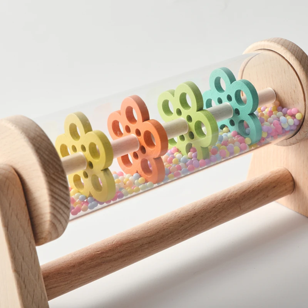 Detailed view of yellow, orange, green, and teal wheels above multicolored beads inside the rain toy.
