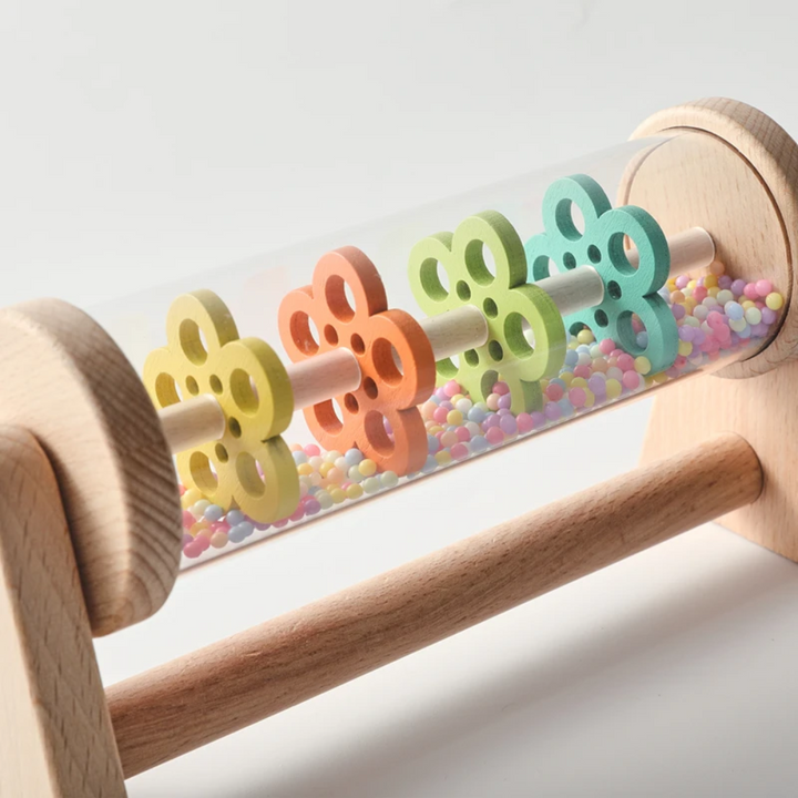 Detailed view of yellow, orange, green, and teal wheels above multicolored beads inside the rain toy.