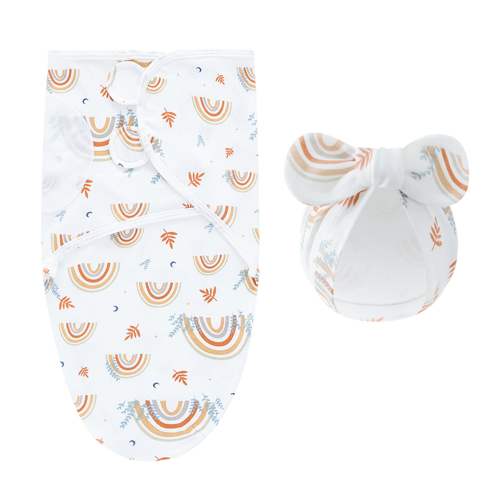 White swaddle blanket and matching bow hat with colorful rainbows and small leaf motifs