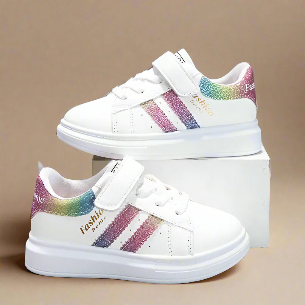 White sneakers with rainbow side stripes and rainbow heel accents displayed on a box.