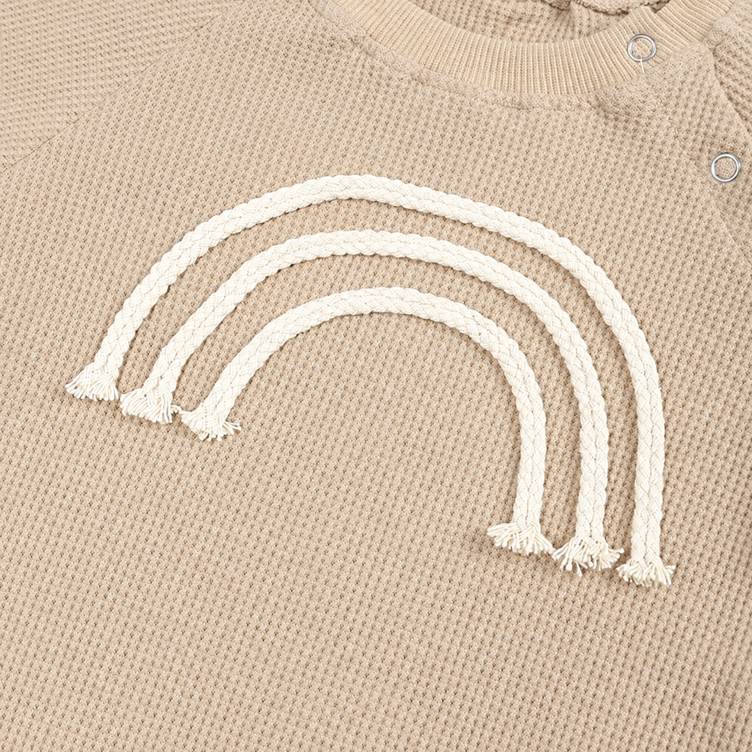 Close-up of raised cream rainbow arches on beige knit fabric