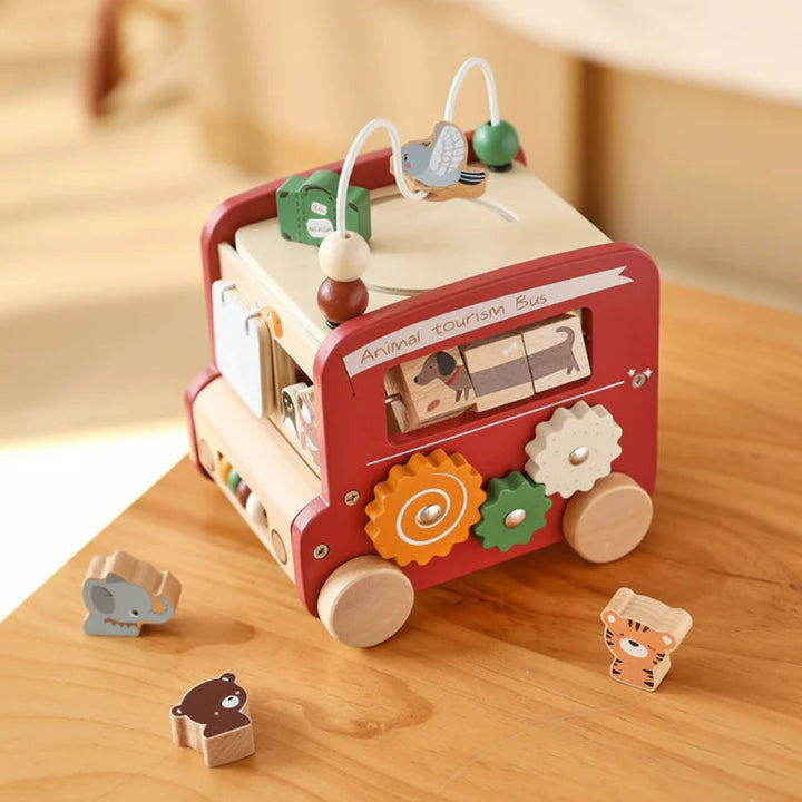 Red wooden activity bus on a table with three animal-shaped blocks