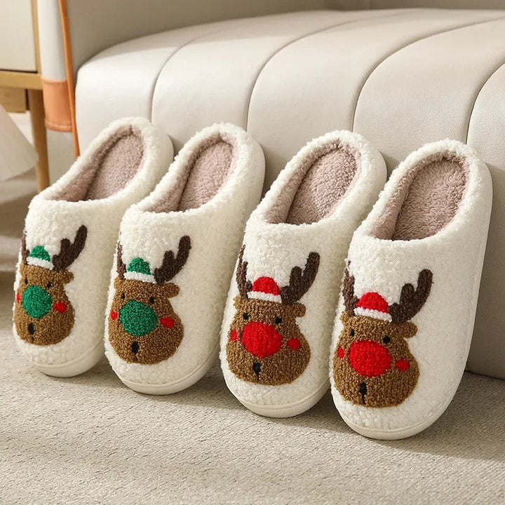 Two pairs of cream plush slippers with red- and green-accented reindeer designs.