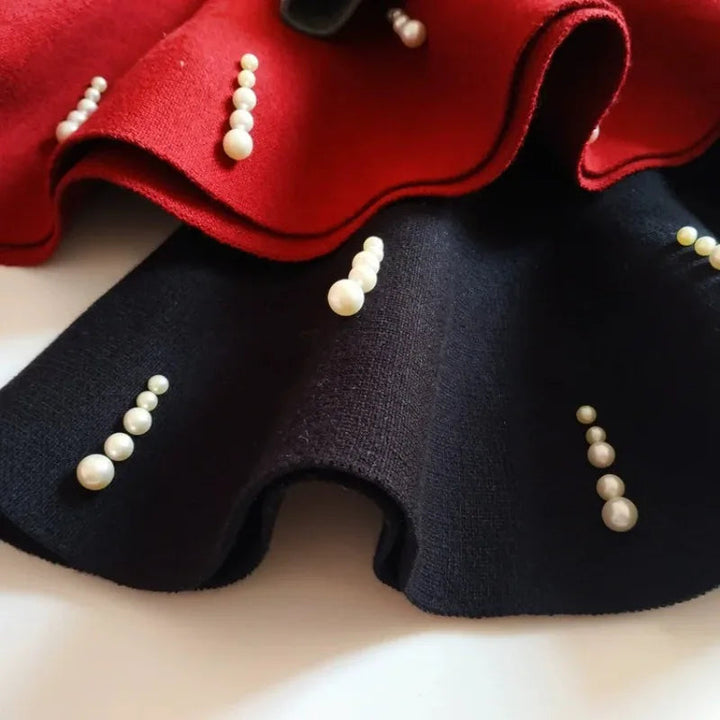 Close-up of red and navy skirt hems with short vertical rows of pearl-style beads