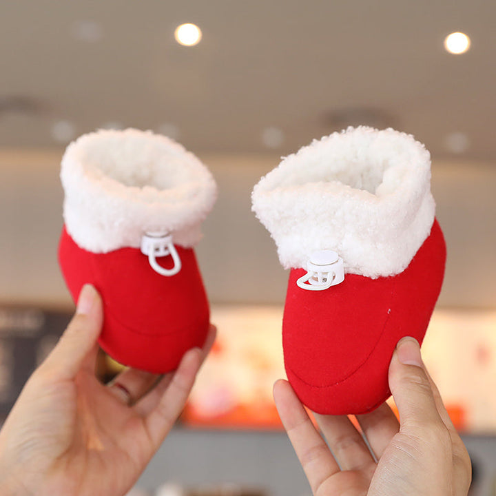 Red baby booties with fluffy white cuffs and front zippers, held in two hands