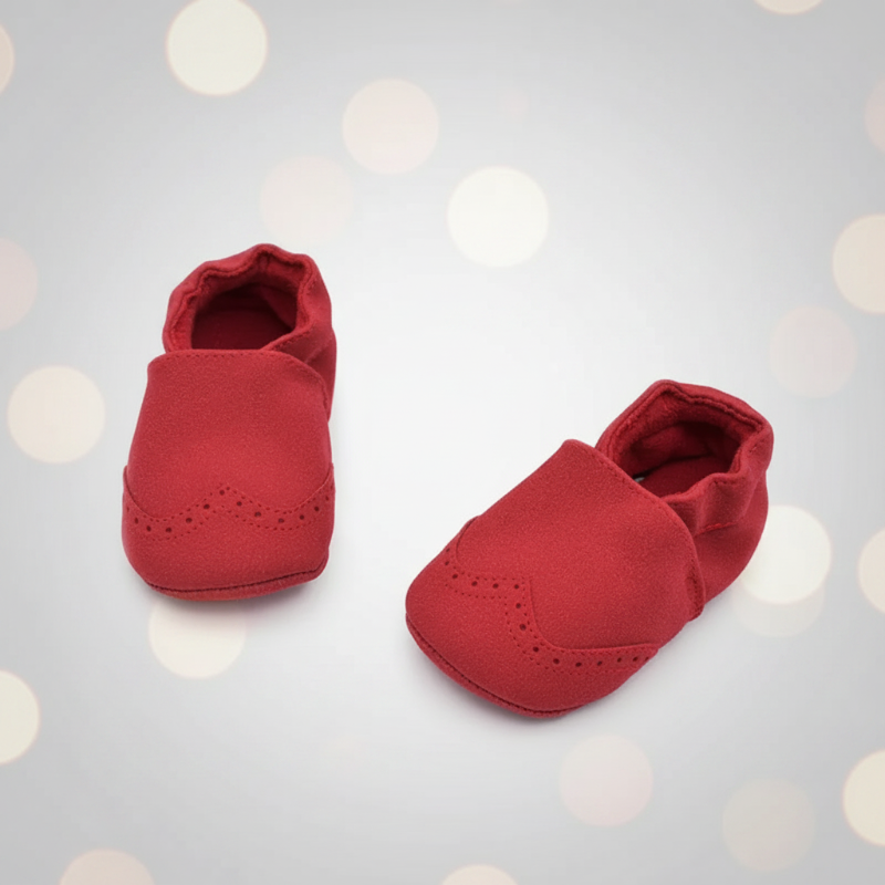 Red baby shoes shown from the front and side on a pale background