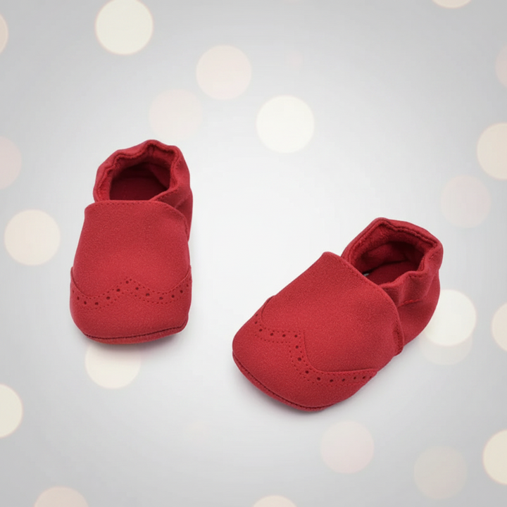 Red baby shoes shown from the front and side on a pale background