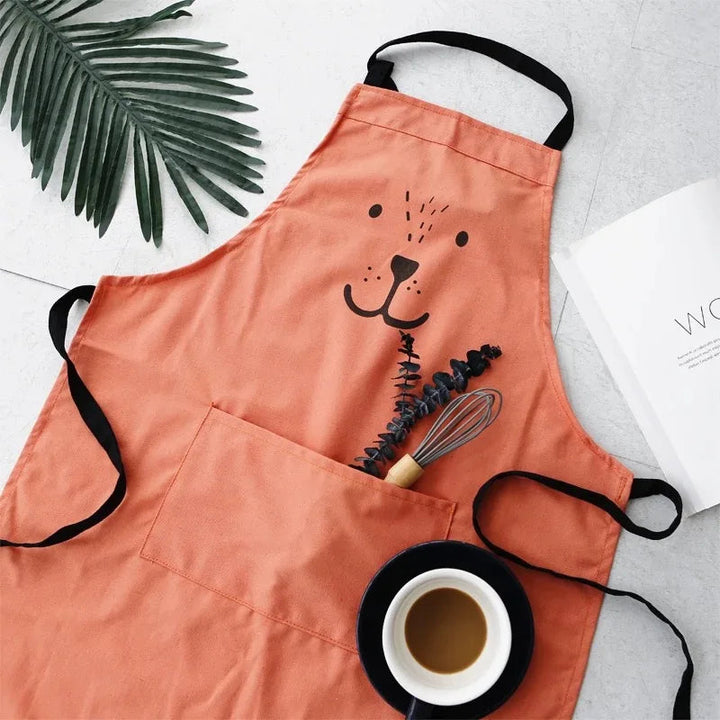 Red bear apron laid flat with a whisk in its front pocket
