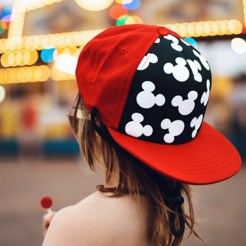 Child wearing a red and black silhouette-print cap against a blurred outdoor background