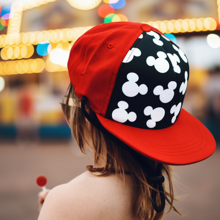 Child wearing a red and black silhouette-print cap against a blurred outdoor background