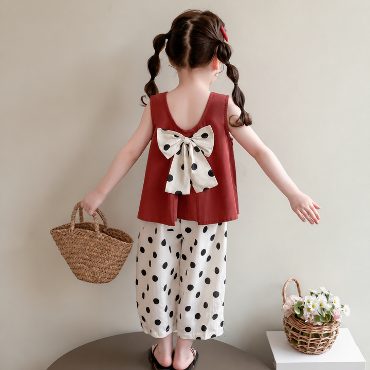Back of a red sleeveless top with a large polka-dot bow and white dotted pants