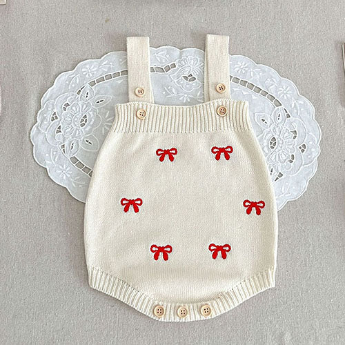 Red bow motifs on a white knit bodysuit with shoulder straps and ribbed edges