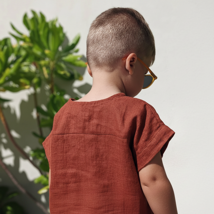 Back view of a boy wearing the red short-sleeve shirt outdoors