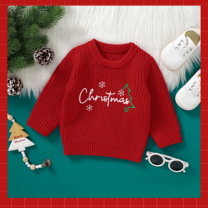Red baby Christmas sweater with white lettering, snowflakes, and a green tree design.