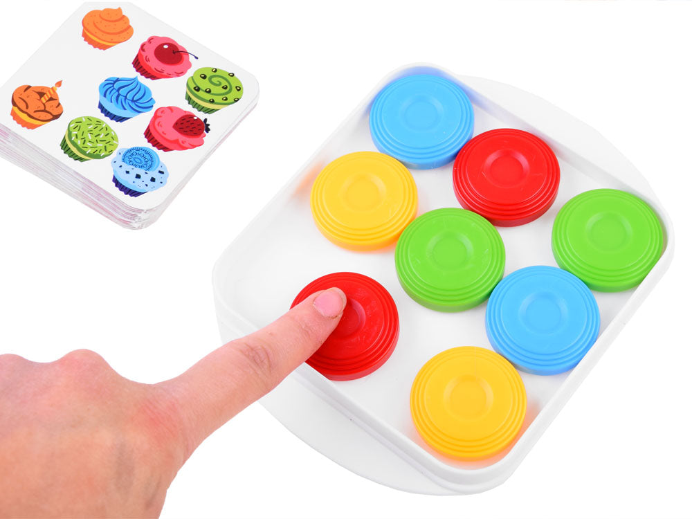 A finger sliding a red disk on a white puzzle board beside a pattern card