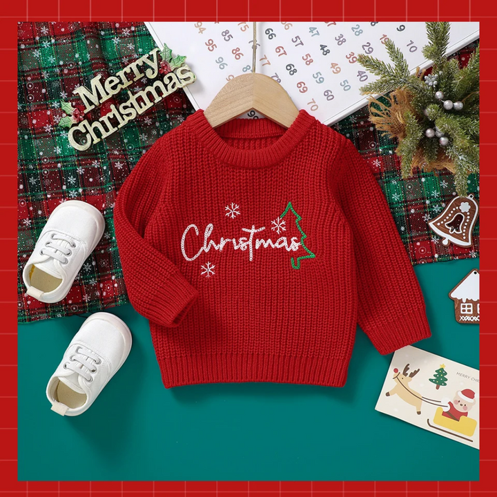 Red embroidered Christmas sweater on a wooden hanger with festive decorations.