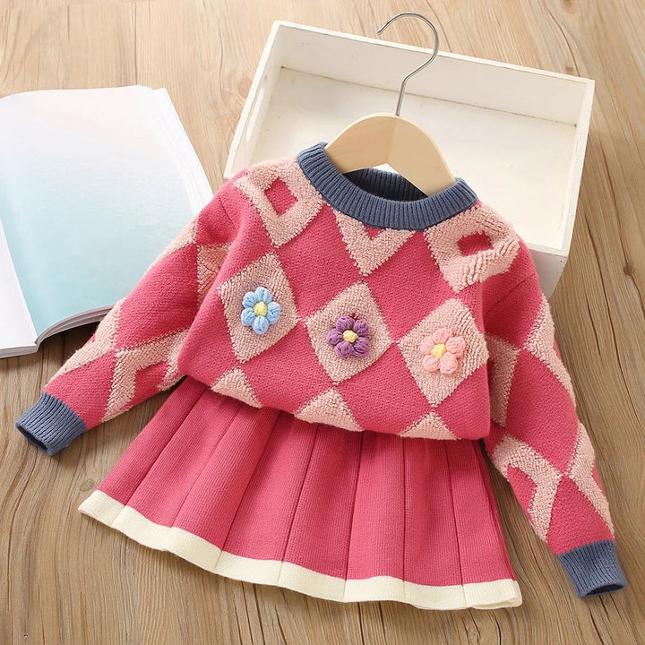 Red knit sweater with blue ribbed trim, raised flowers and a matching pleated skirt