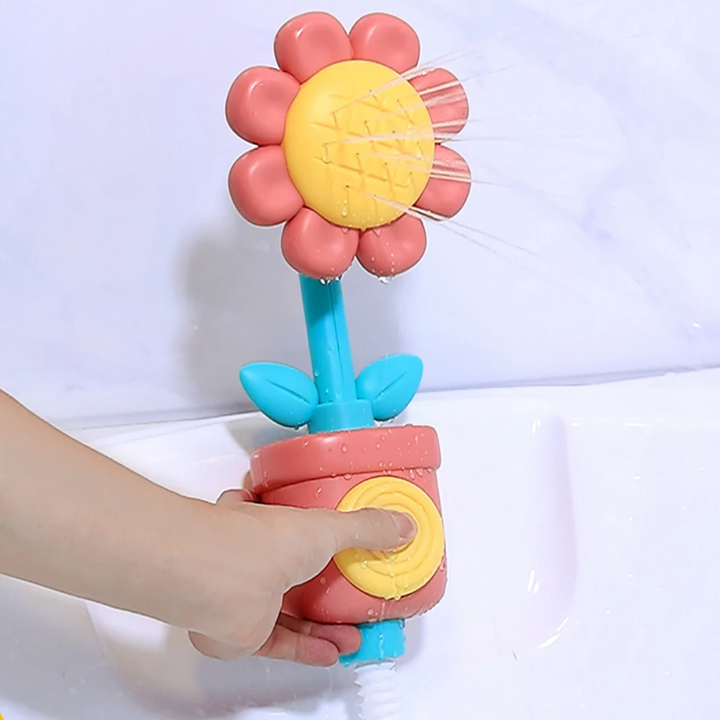 Red flower bath toy with a turquoise stem and a yellow button being pressed to spray water