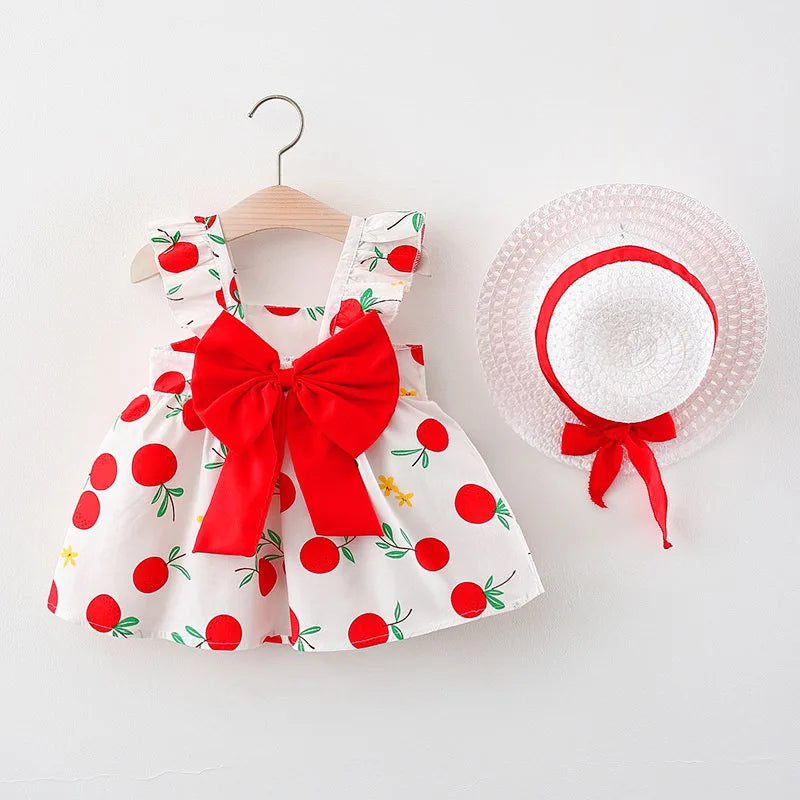 Red fruit-print dress with a large red bow and white straw hat with red ribbon