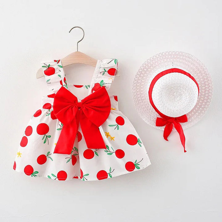 Red fruit-print dress with a large red bow and white straw hat with red ribbon