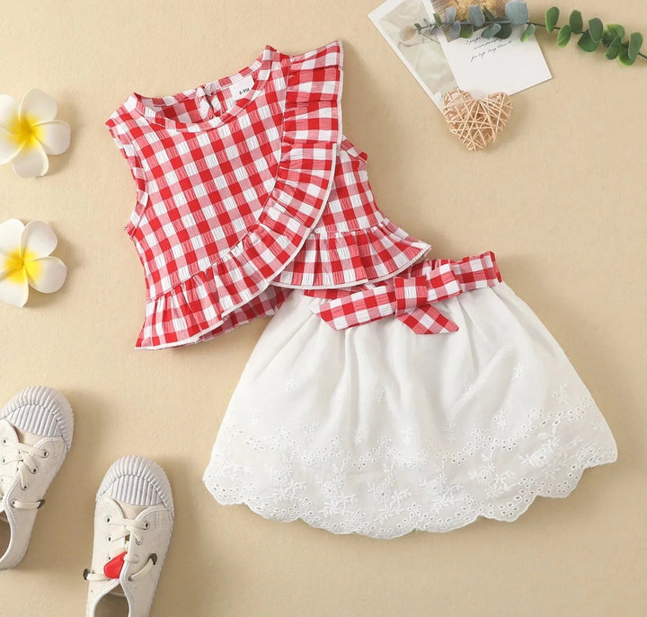 Red gingham sleeveless top with a white scalloped eyelet skirt and red check bow