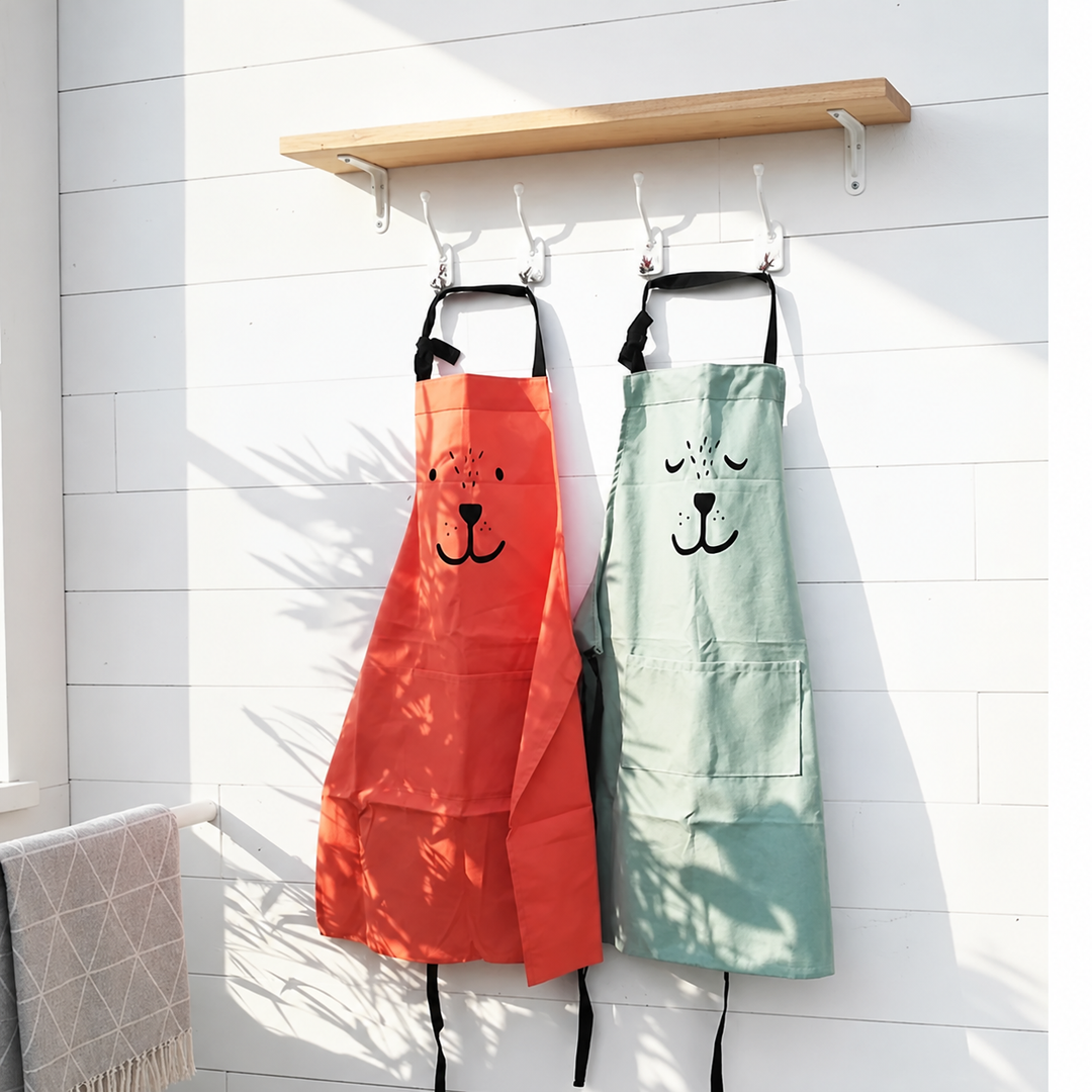 Red and green bear aprons hanging beneath a shelf in sunlight