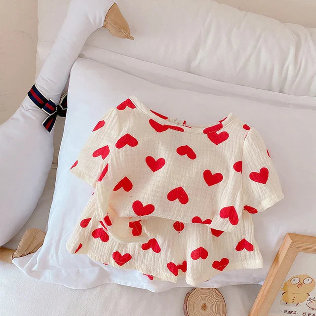 Matching red heart-print top and shorts arranged beside a goose-shaped cushion