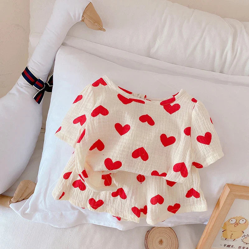 Red heart-print cotton top layered over matching shorts on white bedding