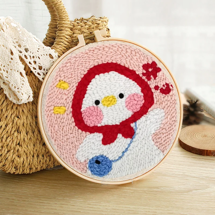 Duck punch needle hoop with a red hood and a pink background