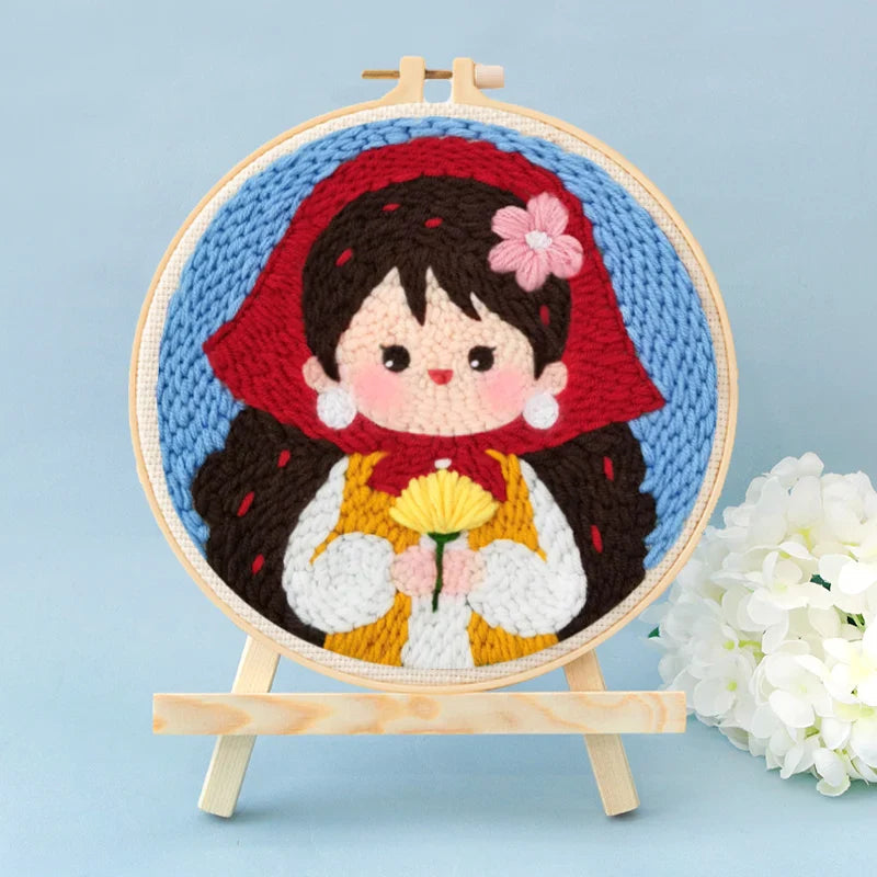 Finished punch needle hoop of a red-hooded girl holding a yellow flower