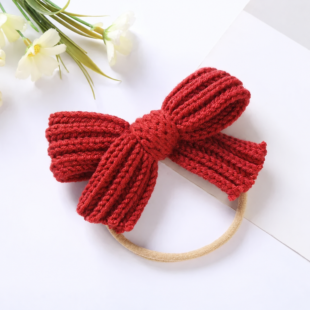Red knitted bow headband showing its textured loops and wrapped center