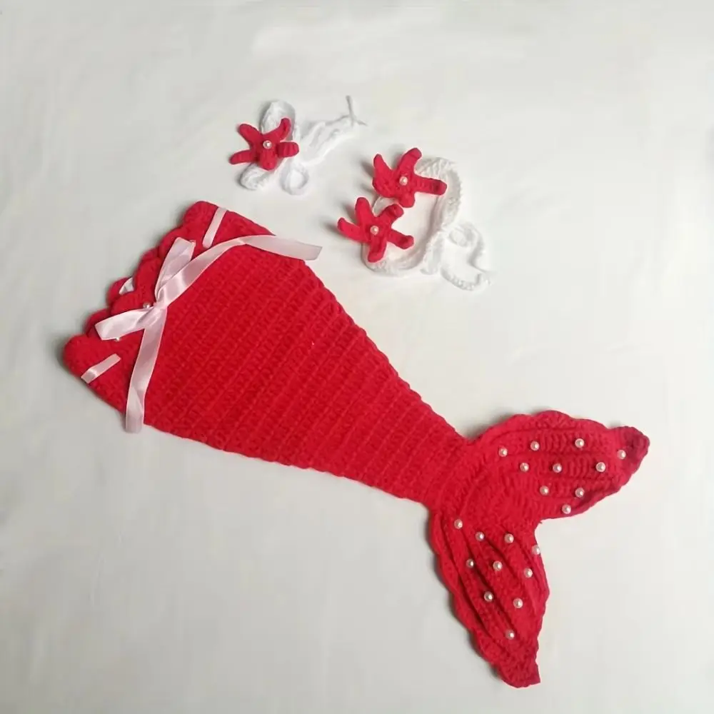 Red knitted mermaid costume arranged flat with its wide fin, starfish top, and headband