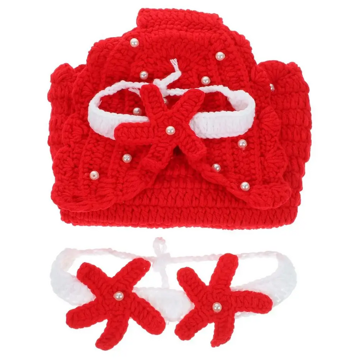 Folded red knitted mermaid tail with a starfish headband and matching top on a white background